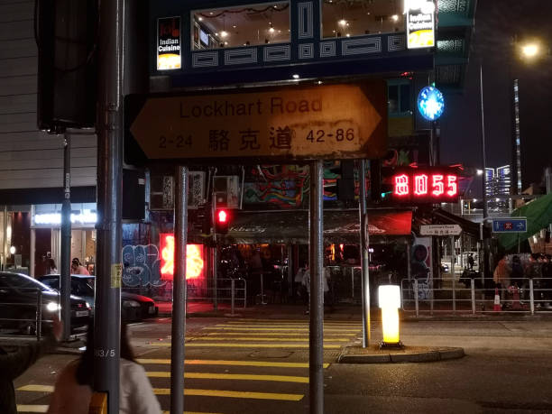 People walking by the many neon signs on Lockhart road by night, a main street through Wanchai district and a nightlife area of Hong Kong island.